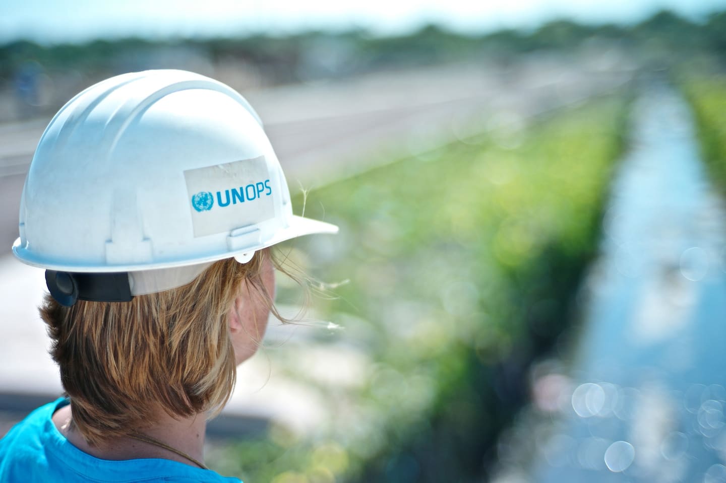 A UNOPS field officer in a hard hat looking out over a project site