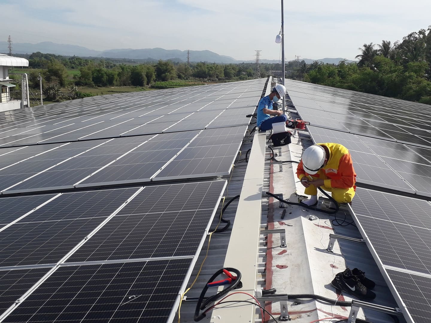 Technicians wiring panels on a large rooftop solar installation